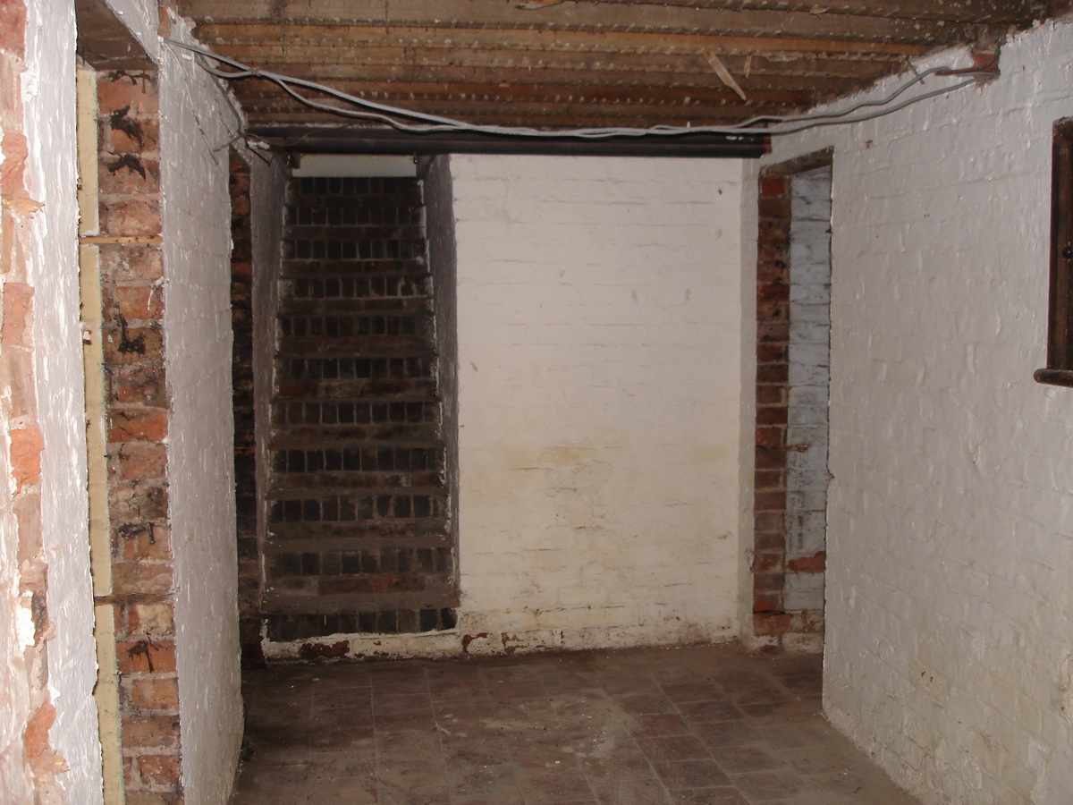 Reverse view of current basement hallway showing existing stairway.