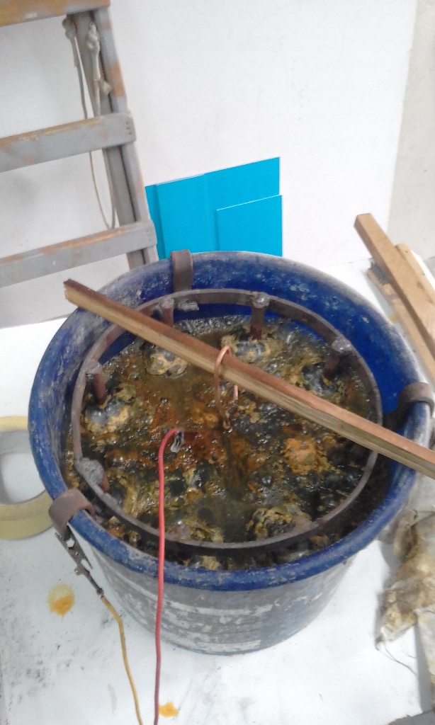 This pic shows the iron inserted into the water,and the charger connected with the +positive to the rusted part and the - negative  to the circle of iron re bar around the inside of the bucket. here bubbles start forming at the negative and the water starts to get a rusty greenish tint.