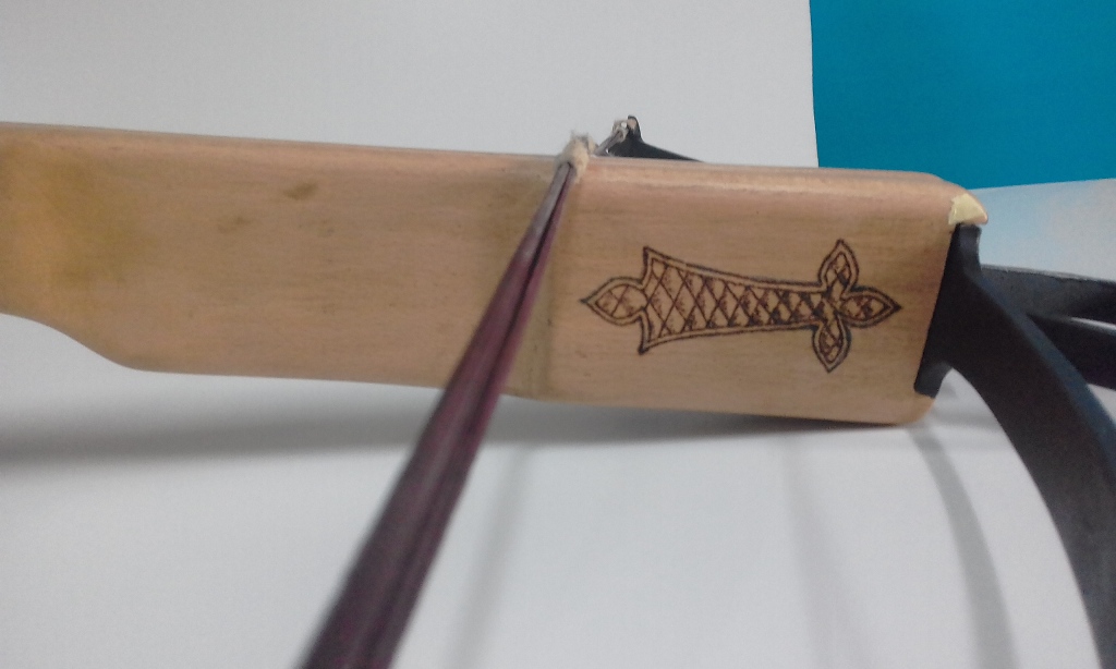 A closeup of the decoration burned on the front part of the crossbow.